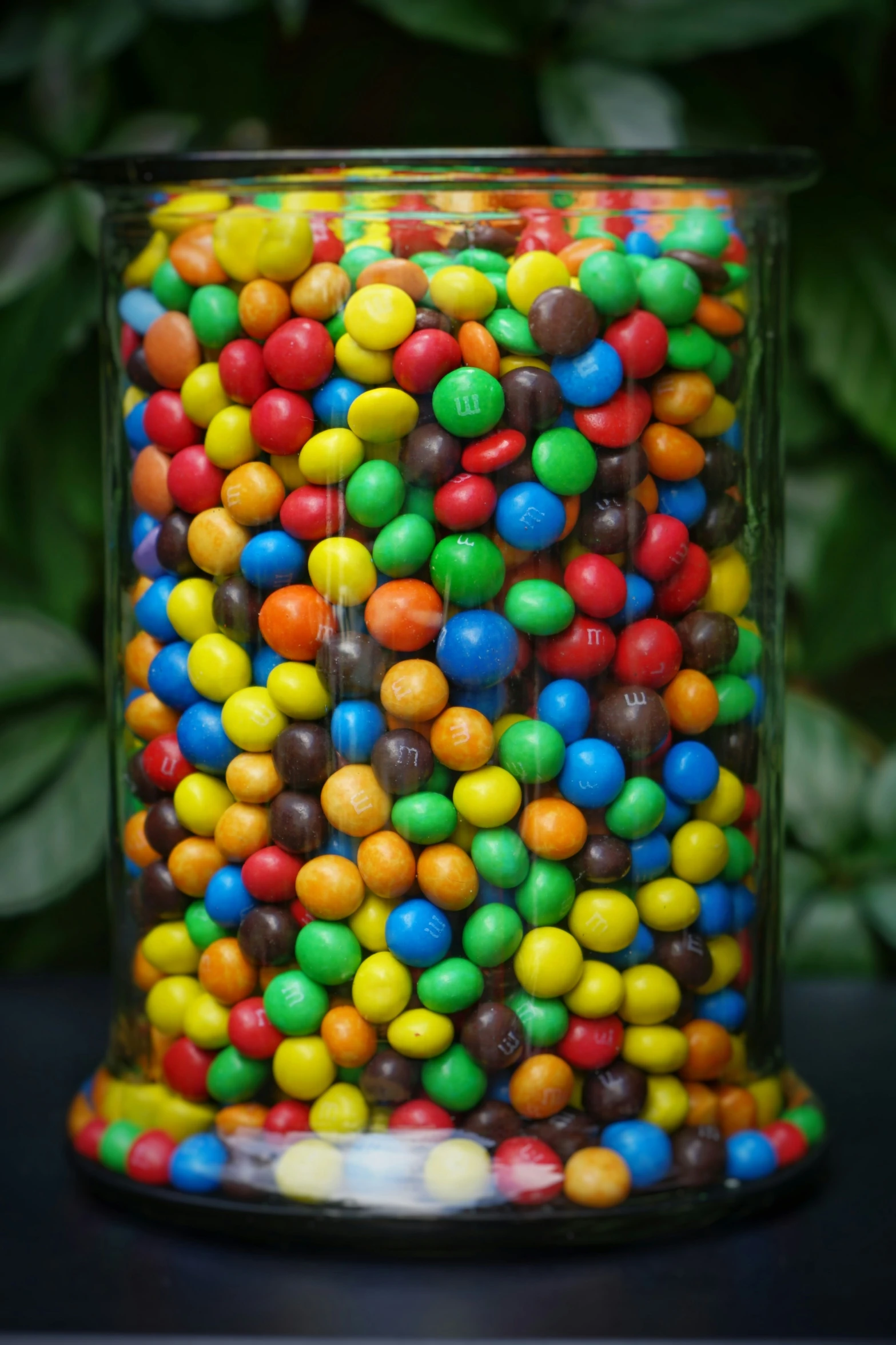 a glass filled with multi colored chocolate beans