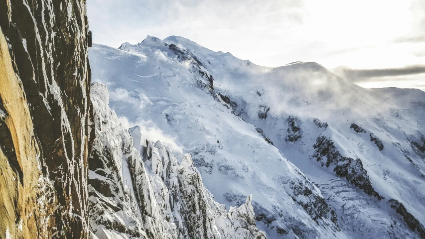 a view of snowy mountains and clouds from a mountain peak