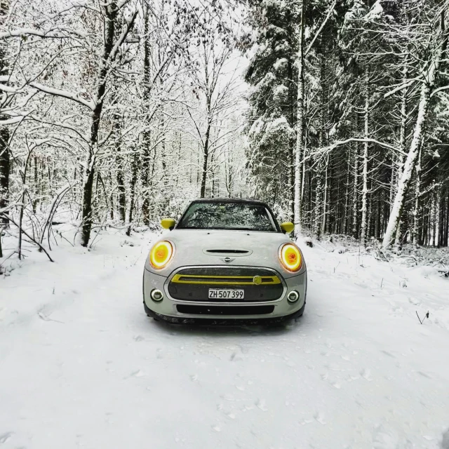 a car is driving on the snow in front of some trees