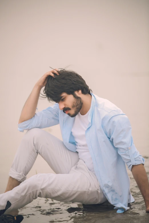 a man sits on the beach while holding his hands to his ears