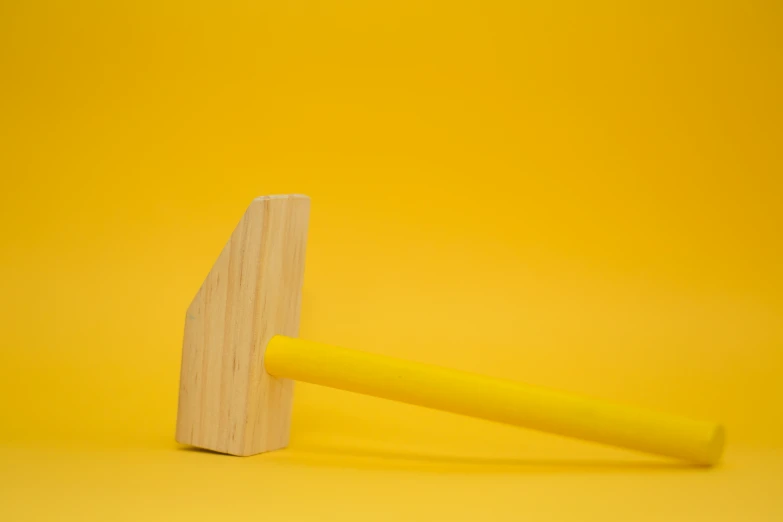 wooden toothpick resting on yellow background, viewed from above