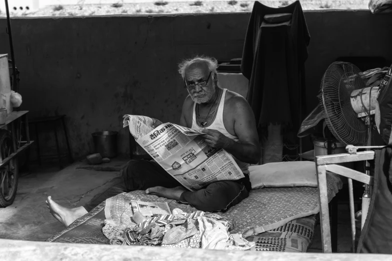 a man sitting on a floor with paper and a fan