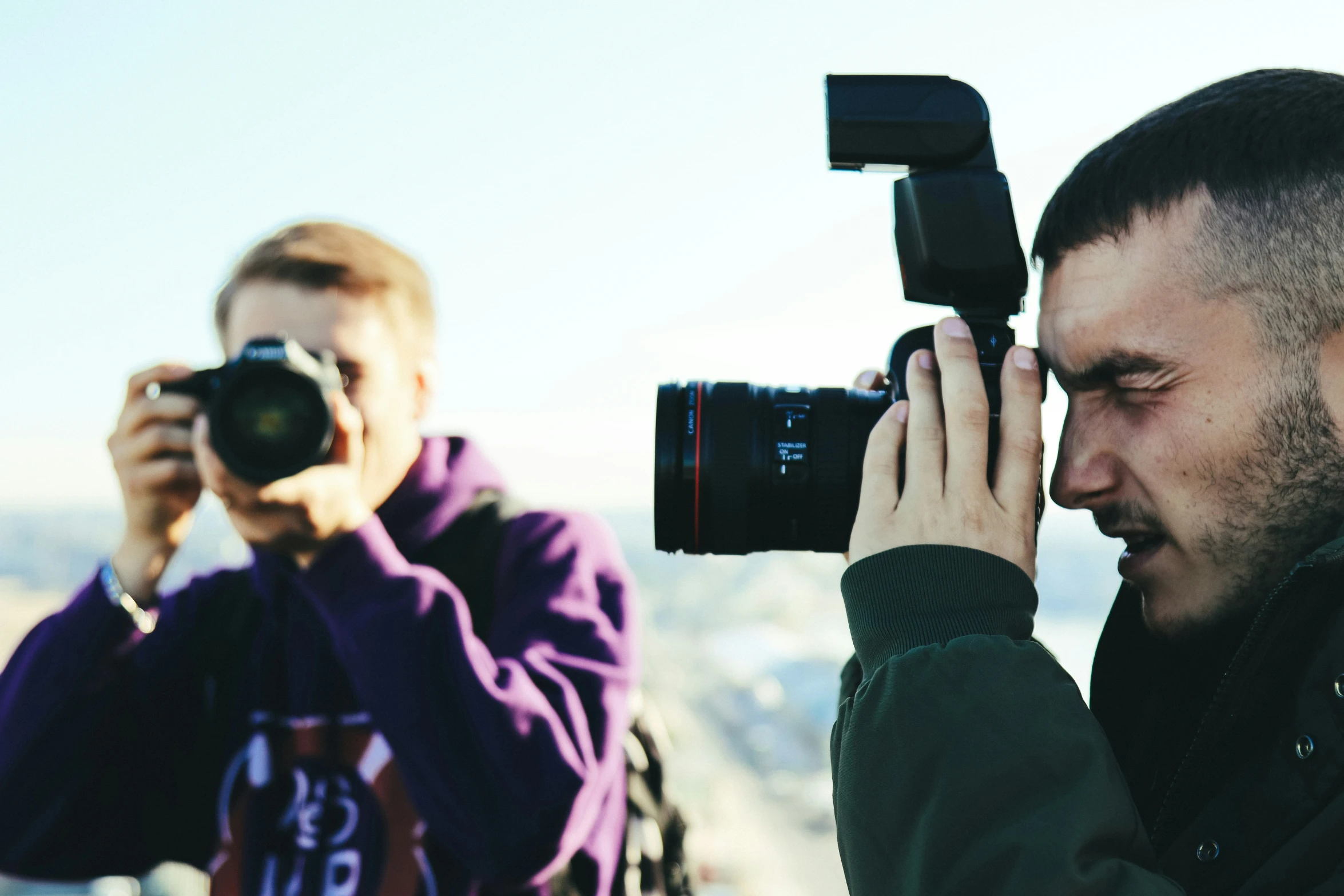 a man holds up his camera for the woman's eye to take a picture