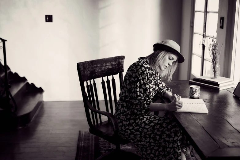 a black and white image of a woman with a book sitting in a chair