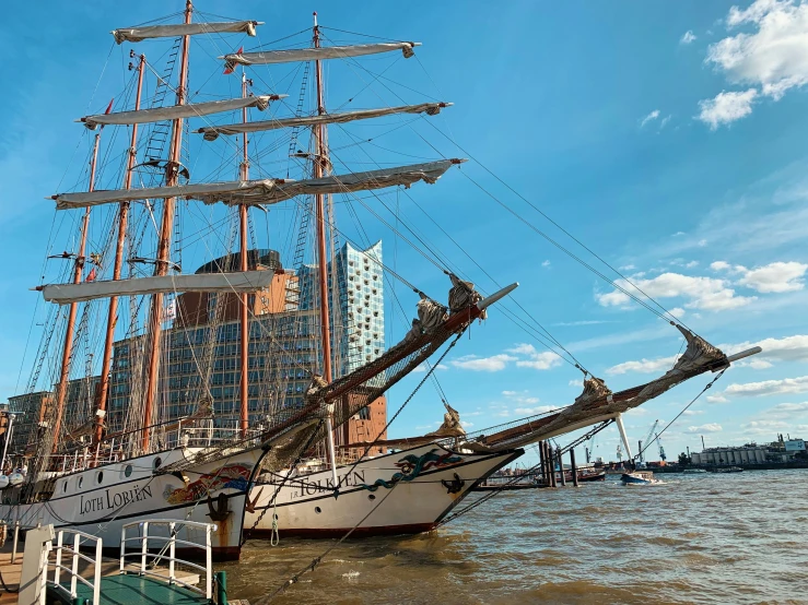 two sail ships on the water near a city