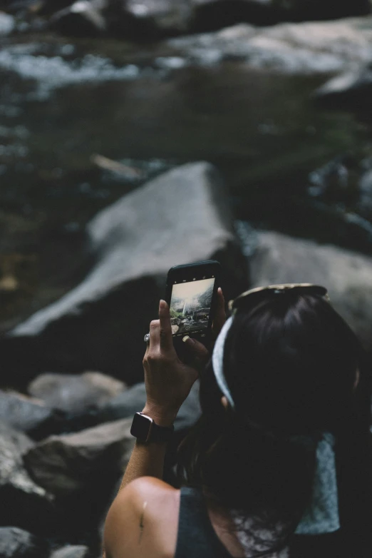 a woman standing near a river taking pictures