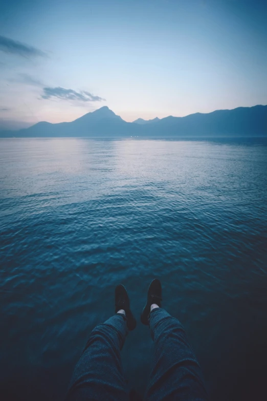 a person sitting in the ocean with his feet up