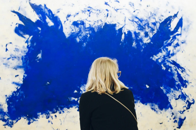 woman looking at blue abstract painting in background