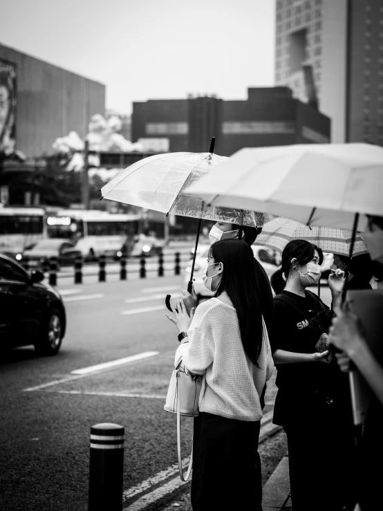 a black and white po of women carrying umbrellas on the street