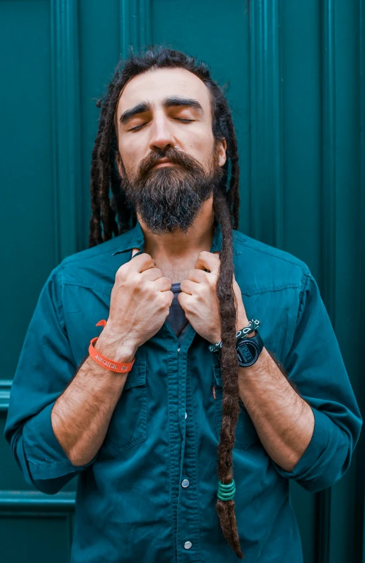 man with long dreadlocks and tie standing near a green door