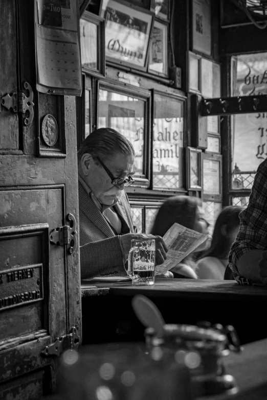 black and white po of men in a bar with newspaper