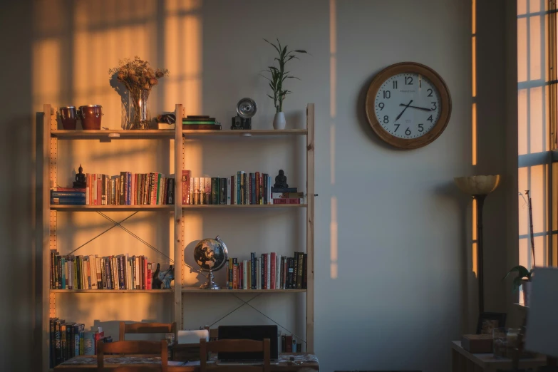 a bookcase with a clock is near the window