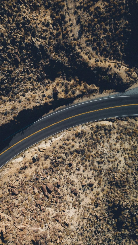 an aerial view of a curved road and trees