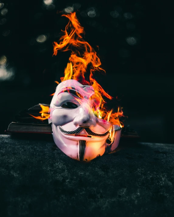 fire burning around a mask and a candle