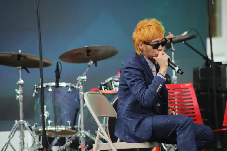a man with orange hair on stage singing into a microphone