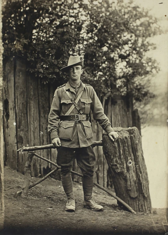 a soldier poses with two spears in front of a fence