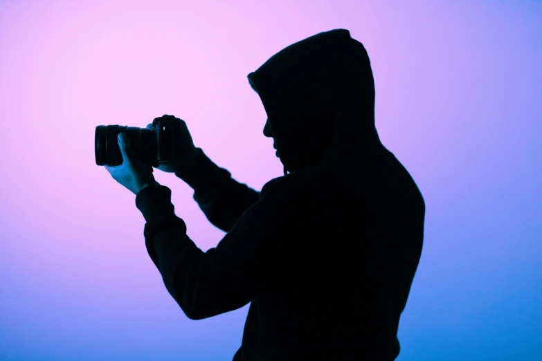 a hooded man taking a picture with his camera