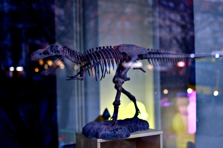a statue of a dinosaur stands in front of a window
