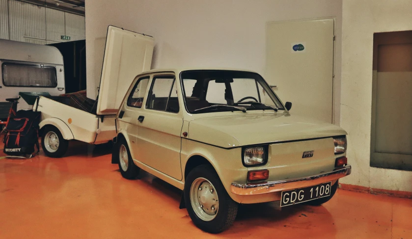 two old cars parked in a room, one has a refrigerator