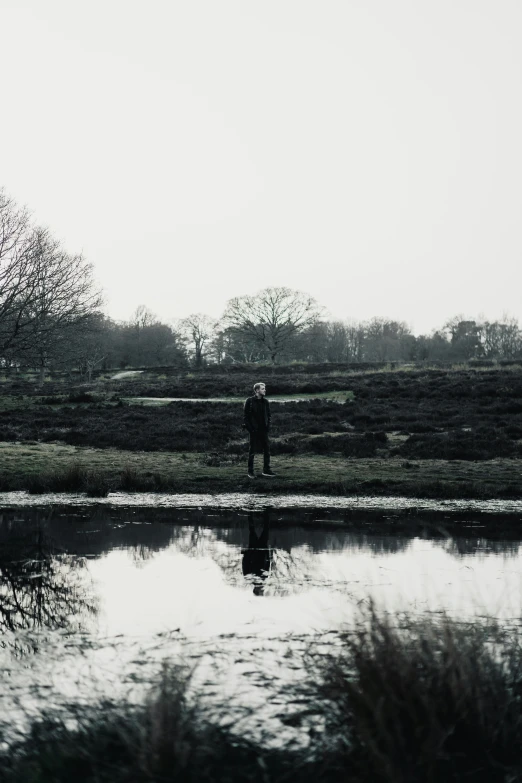 a man in a black and white po standing next to a river