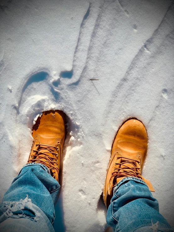 the legs and yellow sneakers of a person are standing in the snow