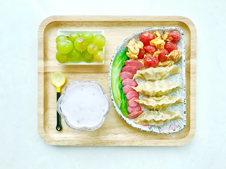 a plate with cheese, fruit and dip