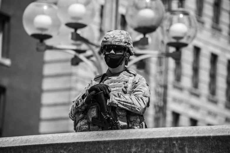 a soldier in camouflage holding his arms crossed