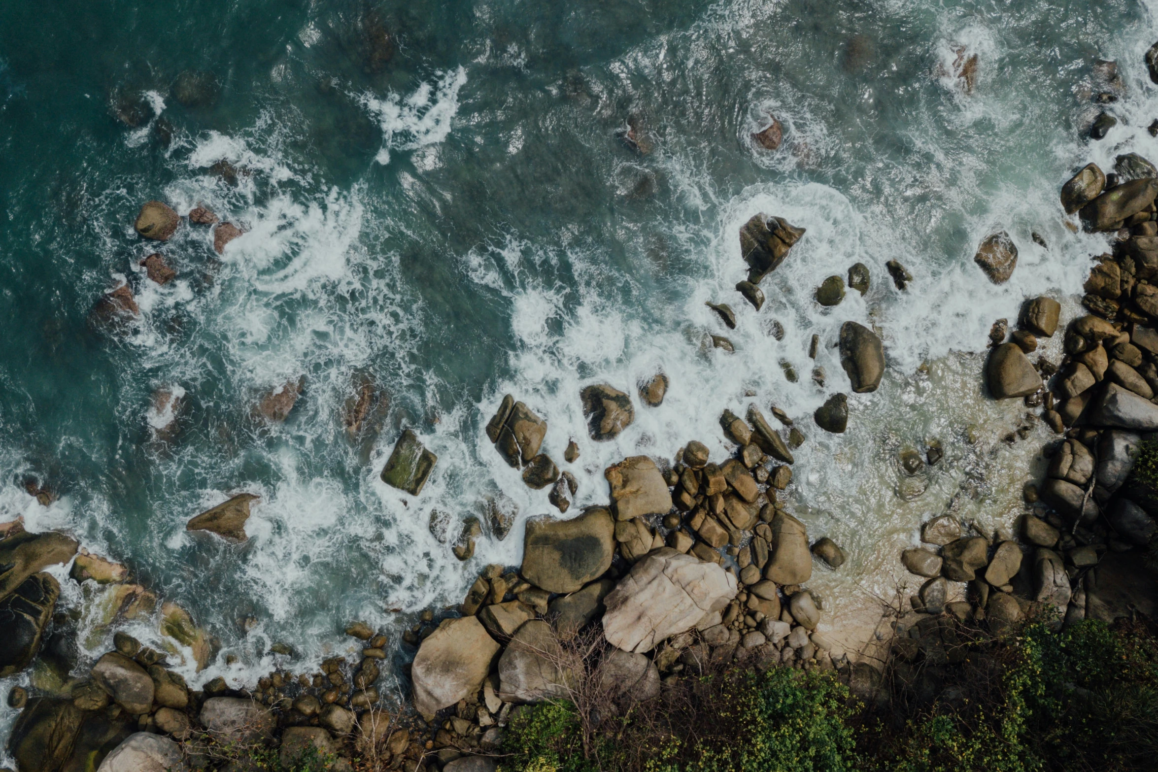 an ocean view from a high above looking down at rocks on the shore