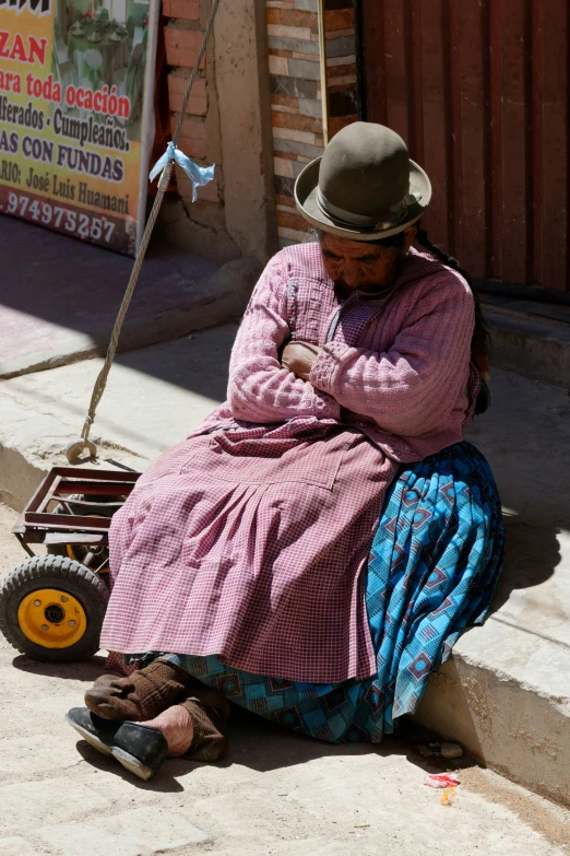 a woman sitting in front of a sign on the sidewalk