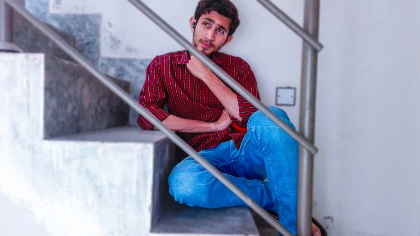 a young man sitting on the stairs with his legs crossed