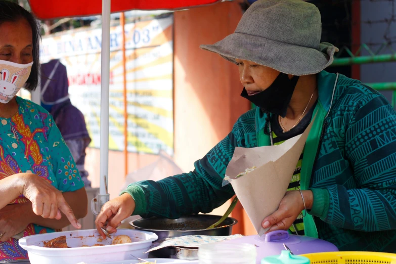 two woman standing at a table with food