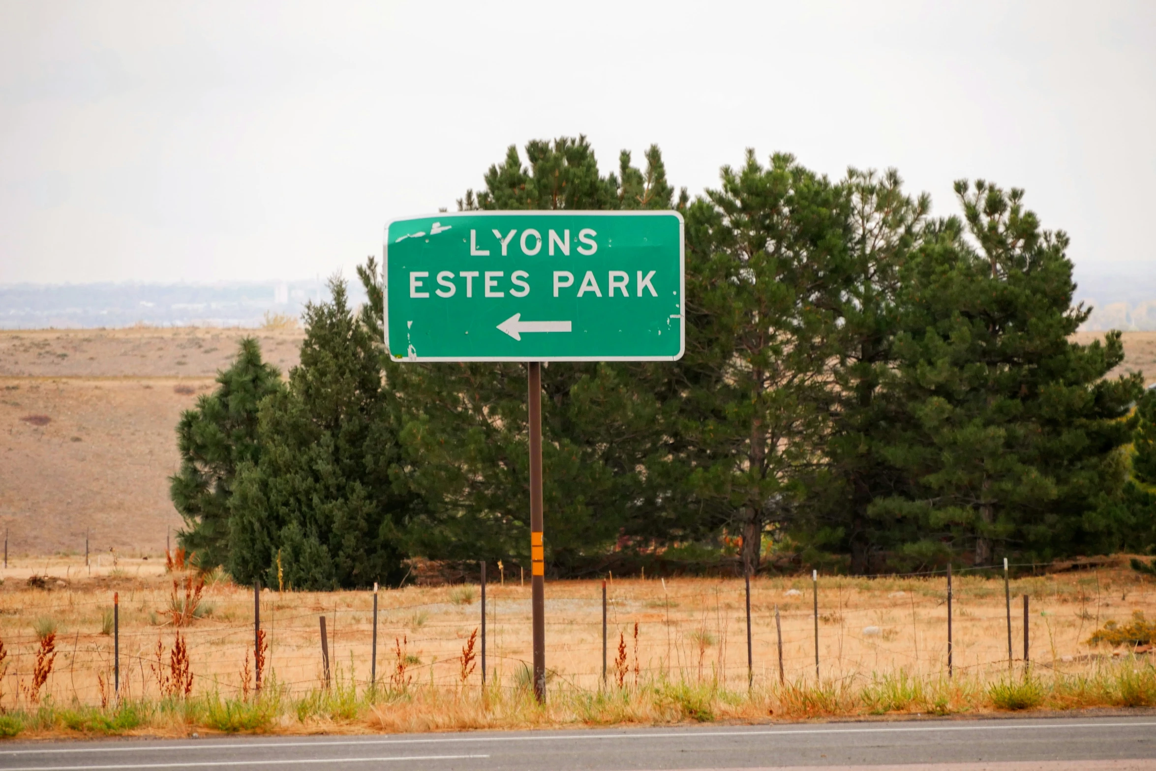 an empty road sign is on the side of a fence