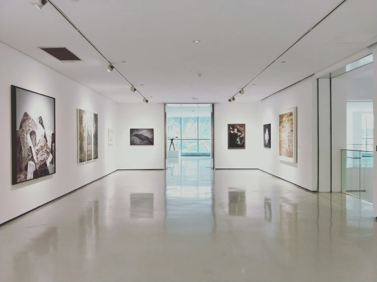 a long hallway is full of white walls and pictures