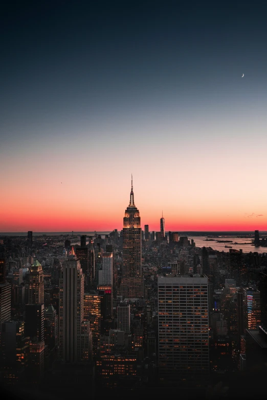 a city is lit up at sunset in the distance