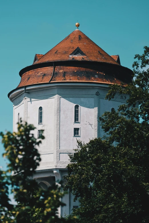 an old water tower is visible between a tree's nches