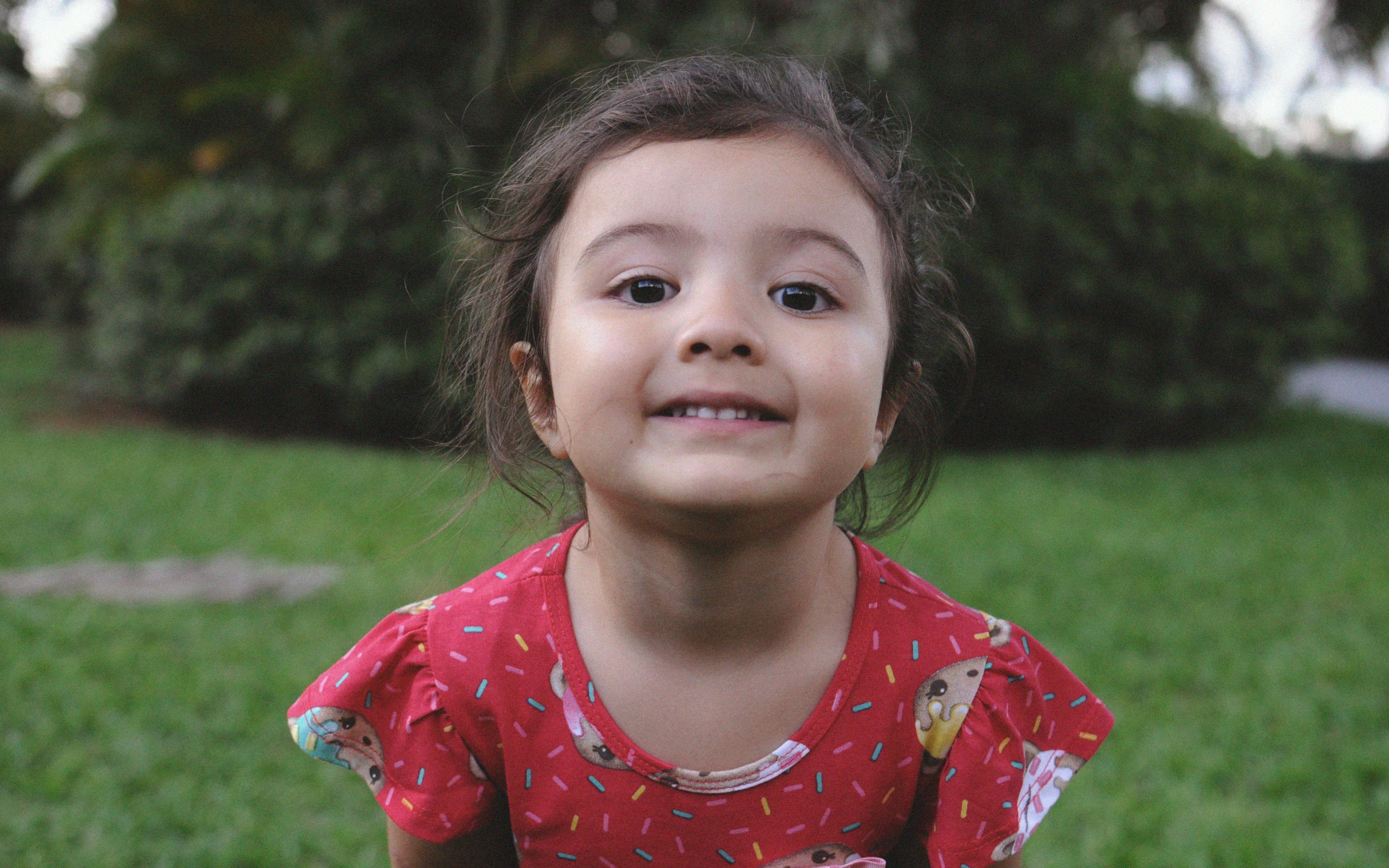 a small girl smiles as she holds an apple