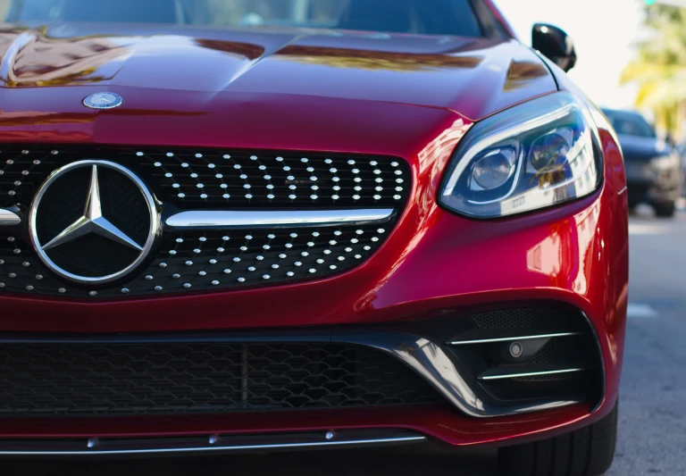 a close up po of the hood of a red mercedes benz coupe