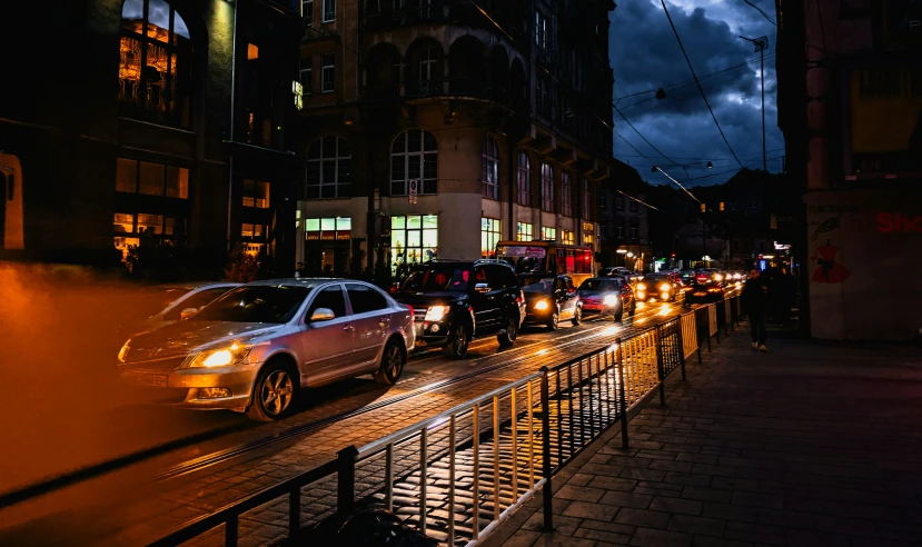 a busy city street at night with a variety of cars passing on it