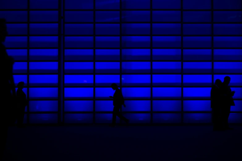 people walking by a wall with a blue window