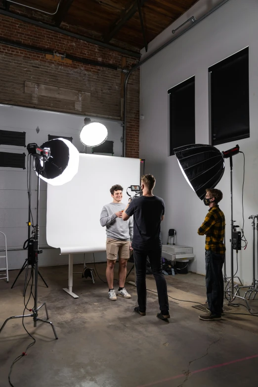 a group of people stand in a studio with lighting equipment