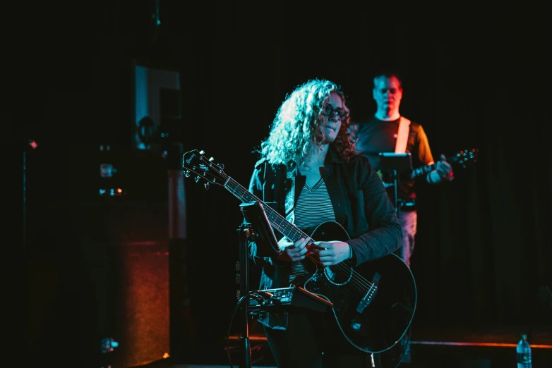 a woman with long white hair and glasses playing guitar