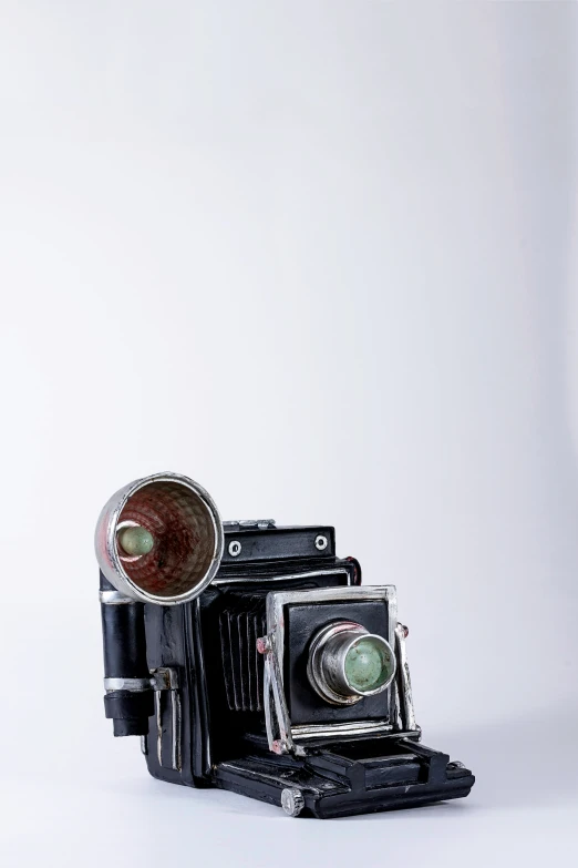 an old fashioned camera has a metal tube that holds a green lens