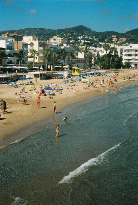 the beach is crowded with lots of people and many buildings