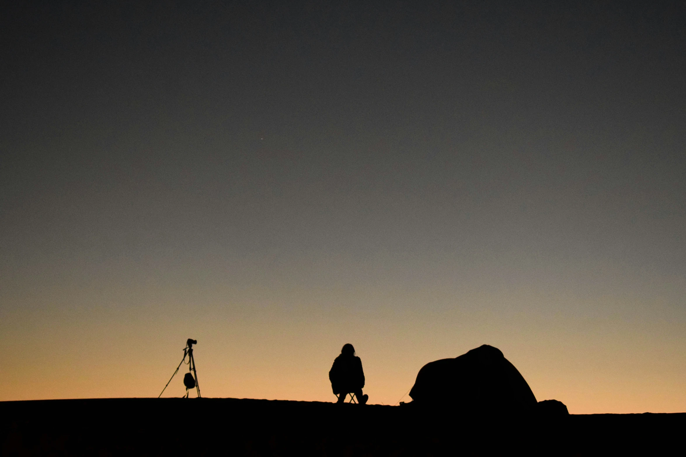 a person is standing alone on the hill at sunset