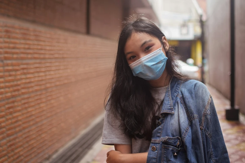 woman wearing a mask while standing against a brick wall