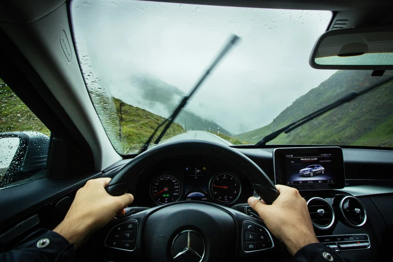 a person in a car driving on a road with mountains