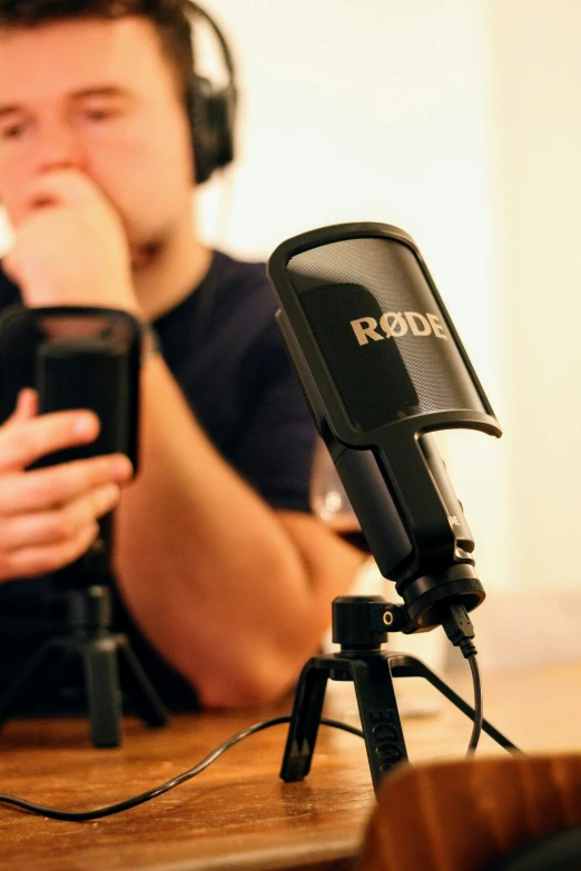 a man sits in front of a microphone while looking at his phone