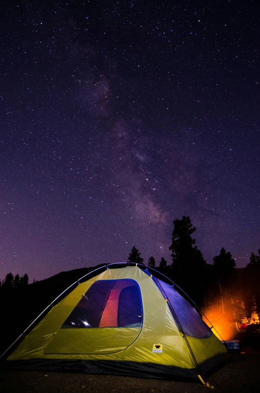 the bright tent sits in a forest at night