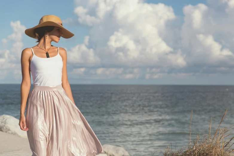 a woman in a hat walking along the ocean