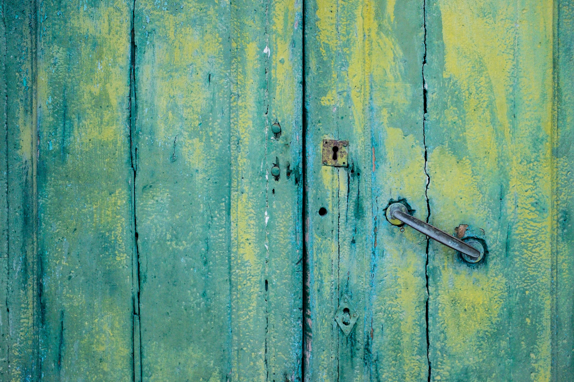 a bright green painted door with a rusty handle